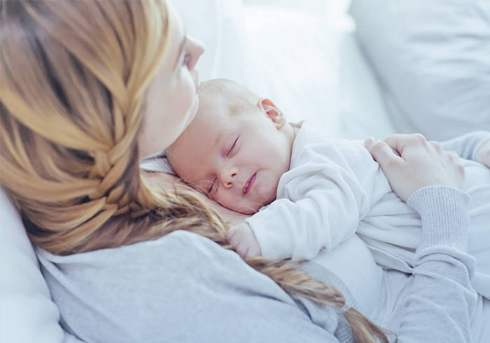 Elisabethen Quelle Stillzeit Frau hält schlafendes Baby in ihren Armen.